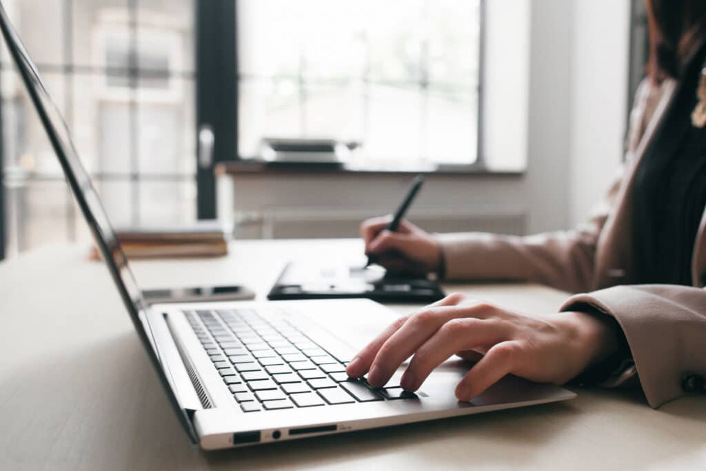 Woman keyboarding on laptop, student work